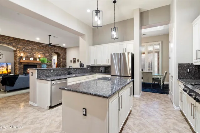 a kitchen with stainless steel appliances granite countertop a stove top oven a sink a dining table and chairs with white cabinets