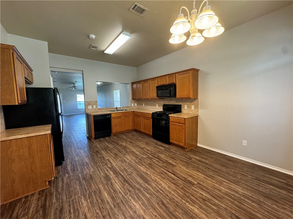 921 Whitewing Lane College Station, TX 77845 - Photo 2 of 14 a kitchen with stainless steel appliances granite countertop a stove top oven a sink dishwasher and a refrigerator with wooden floor