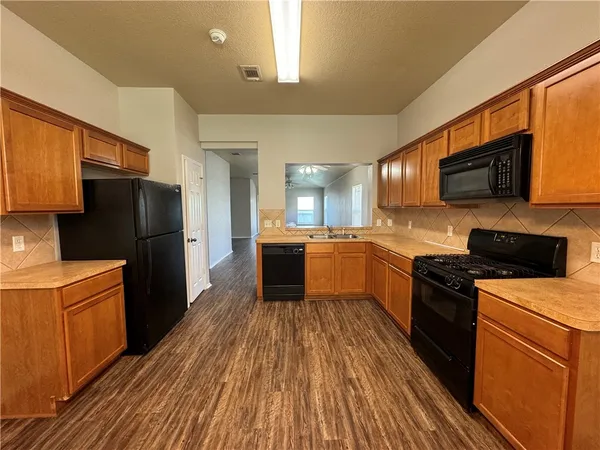 a kitchen with a refrigerator a stove top oven a sink dishwasher and wooden floor