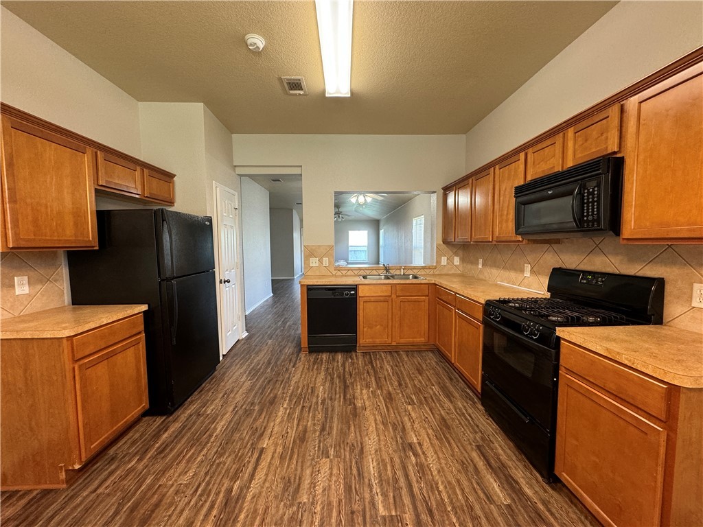 921 Whitewing Lane College Station, TX 77845 - Photo 3 of 14 a kitchen with a refrigerator a stove top oven a sink dishwasher and wooden floor
