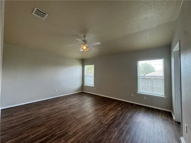 an empty room with wooden floor and windows