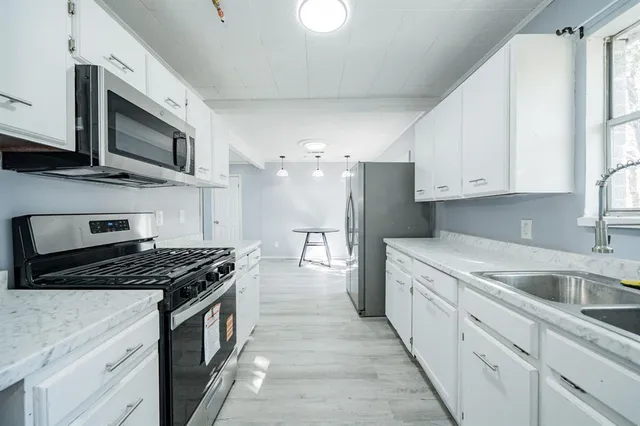 a kitchen with stainless steel appliances granite countertop a stove a sink and a microwave