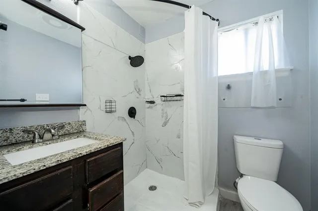 a bathroom with a granite countertop sink toilet and shower