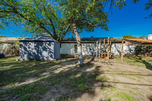 a view of a backyard with table and chairs and a large tree