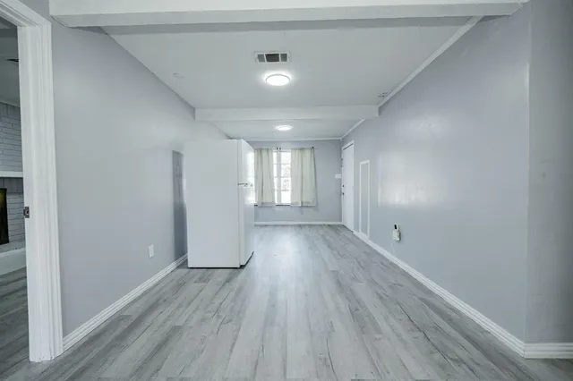 a view of an empty room with wooden floor and window
