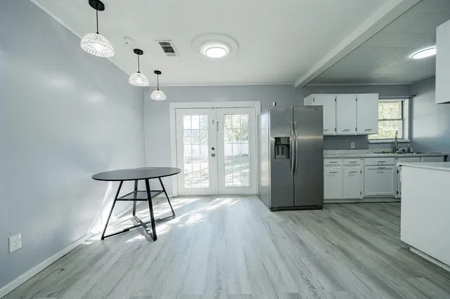 a kitchen with stainless steel appliances a refrigerator a sink dishwasher a stove and white countertops with wooden floor