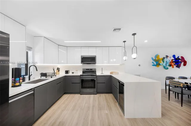 a kitchen with stainless steel appliances a sink dishwasher stove refrigerator and cabinets with wooden floor