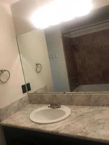 a bathroom with a granite countertop sink and a mirror