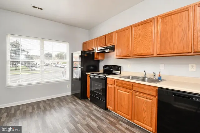a kitchen with a stove top oven a sink dishwasher and a refrigerator with wooden floor