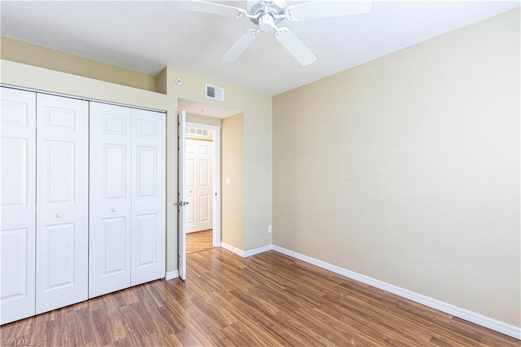 6914 Satinleaf Road North, Unit 102 Naples, FL 34109 - Photo 12 of 24 Unfurnished bedroom featuring wood finished floors, a closet, and ceiling fan