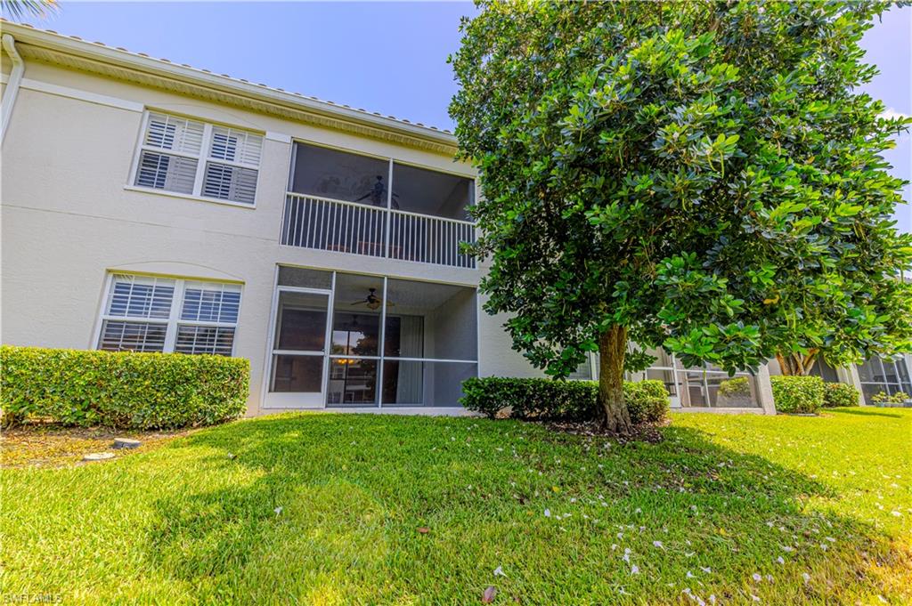 6914 Satinleaf Road North, Unit 102 Naples, FL 34109 - Photo 18 of 24 Rear view of house featuring a sunroom, stucco siding, and a lawn
