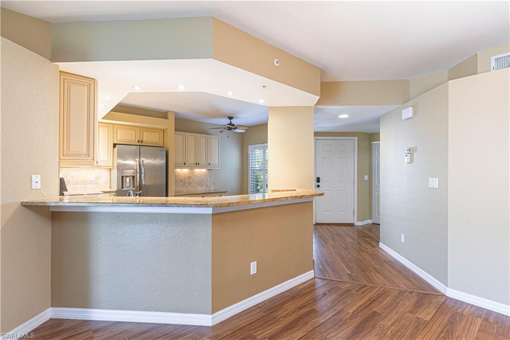 6914 Satinleaf Road North, Unit 102 Naples, FL 34109 - Photo 4 of 24 Kitchen featuring cream cabinets, wood finished floors, stainless steel fridge, ceiling fan, and recessed lighting