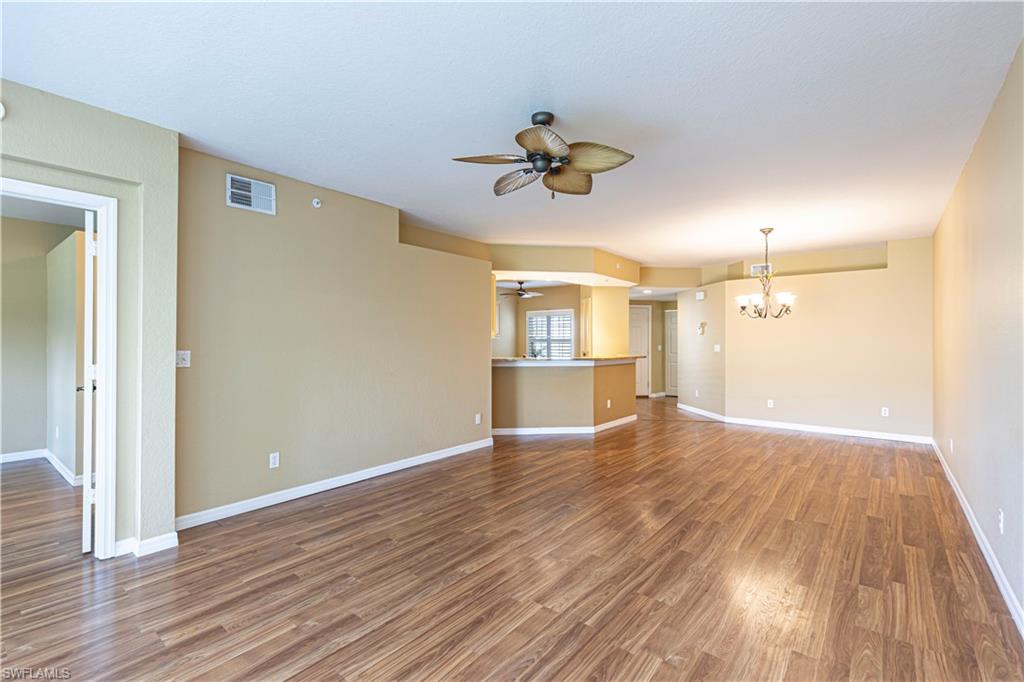 6914 Satinleaf Road North, Unit 102 Naples, FL 34109 - Photo 6 of 24 Unfurnished living room with ceiling fan, a chandelier, and wood finished floors