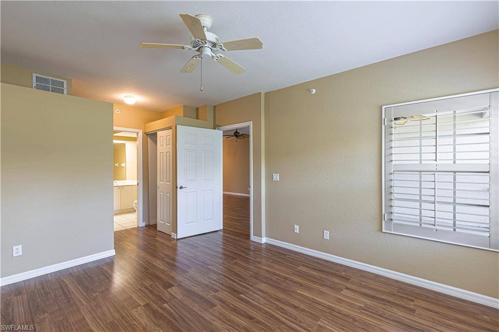 6914 Satinleaf Road North, Unit 102 Naples, FL 34109 - Photo 9 of 24 Unfurnished bedroom with wood finished floors, connected bathroom, and ceiling fan