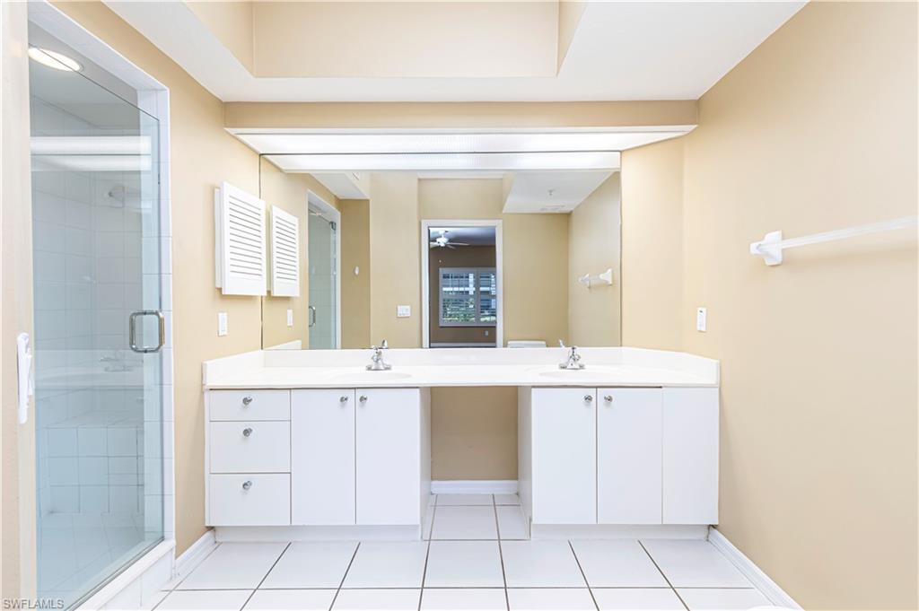 6914 Satinleaf Road North, Unit 102 Naples, FL 34109 - Photo 10 of 24 Full bath featuring double vanity, a shower stall, tile patterned flooring, and a ceiling fan