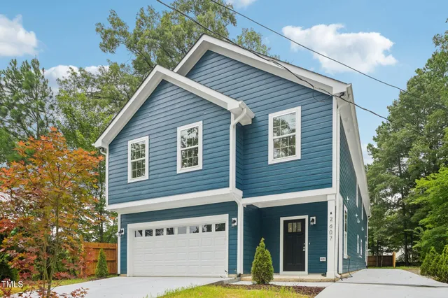 a view of a house with a garage and a tree