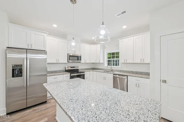 a kitchen with stainless steel appliances granite countertop a sink stove refrigerator and cabinets