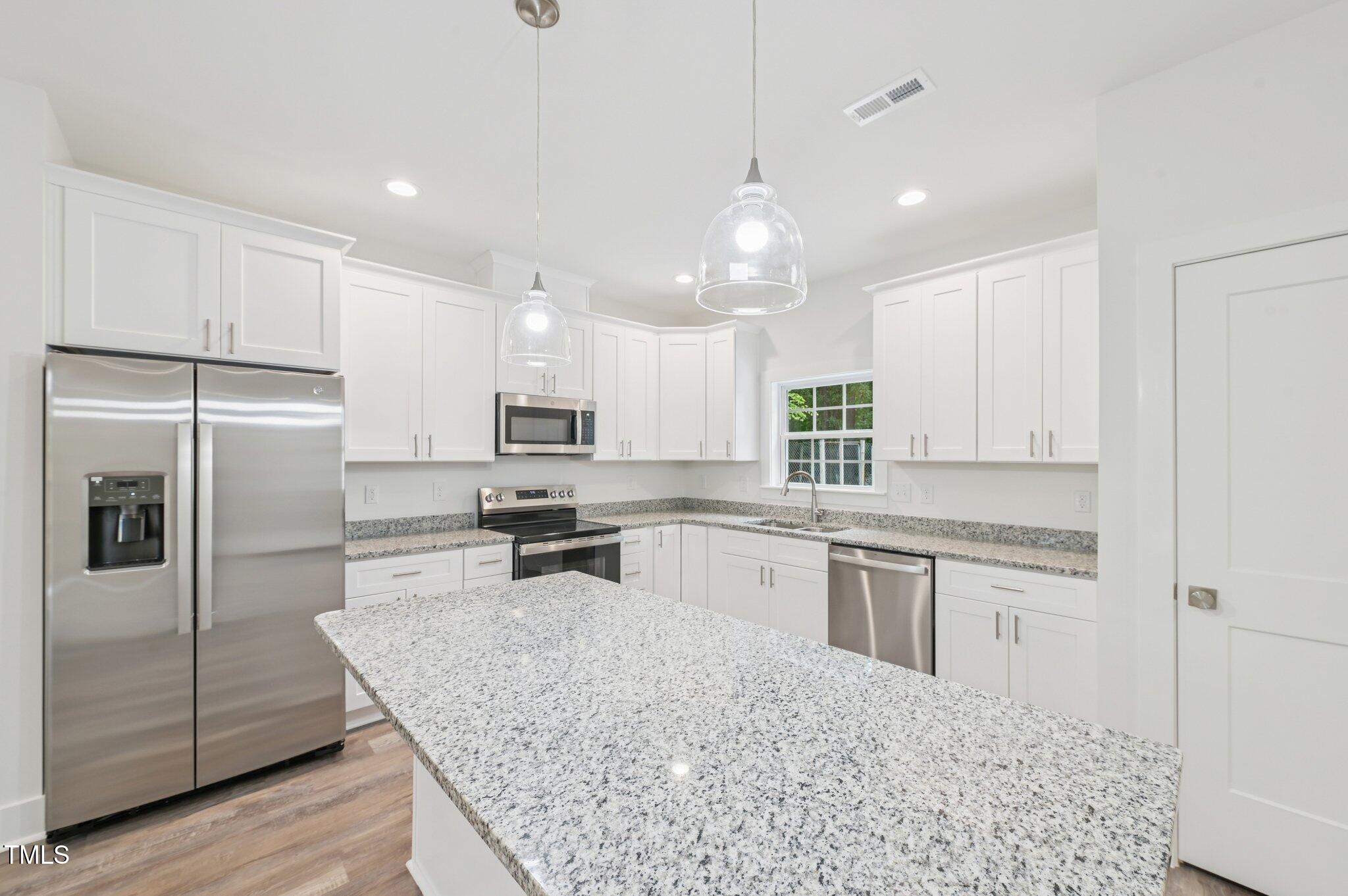 2607 Duke Homestead Road, Unit A Durham, NC 27705 - Photo 10 of 27 a kitchen with stainless steel appliances granite countertop a sink stove refrigerator and cabinets