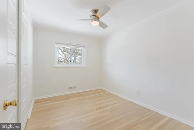 an empty room with a ceiling fan and window