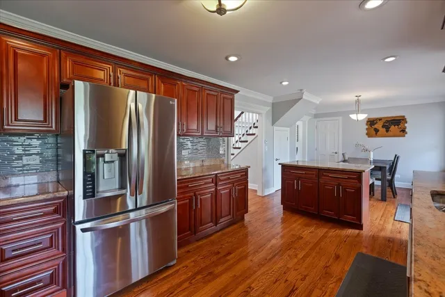 a kitchen with stainless steel appliances granite countertop a refrigerator a stove and a wooden floors