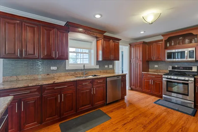 a kitchen with stainless steel appliances granite countertop wooden cabinets sink and stove top oven