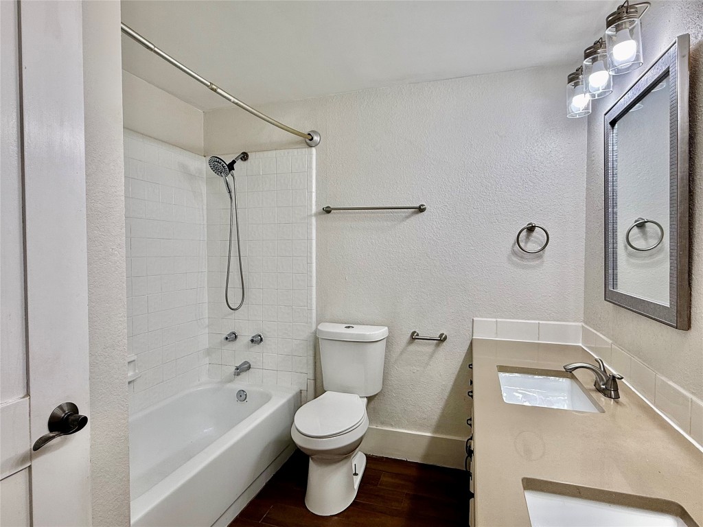 2605 Enfield Road, Unit 103 Austin, TX 78703 - Photo 11 of 17 Bathroom featuring a textured wall, double vanity, dark wood-style floors, and shower / tub combination