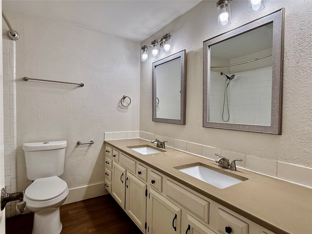 2605 Enfield Road, Unit 103 Austin, TX 78703 - Photo 12 of 17 Bathroom with a textured wall, double vanity, and dark wood-style flooring