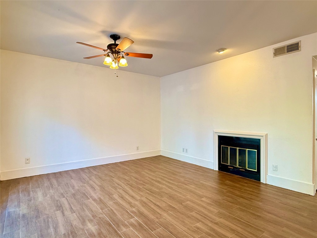 2605 Enfield Road, Unit 103 Austin, TX 78703 - Photo 9 of 17 Unfurnished living room with a glass covered fireplace, ceiling fan, and light wood-style flooring