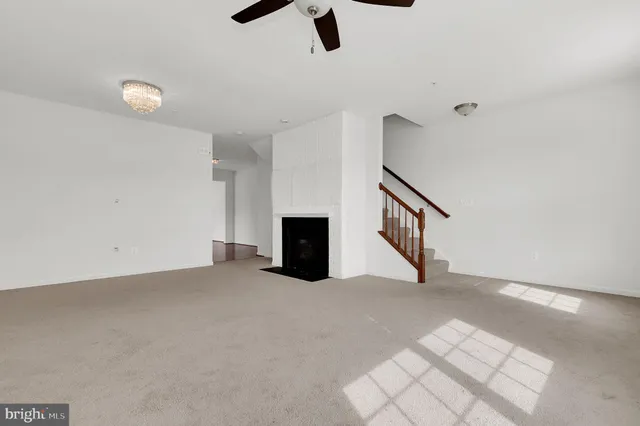 a view of an empty room with chandelier fan