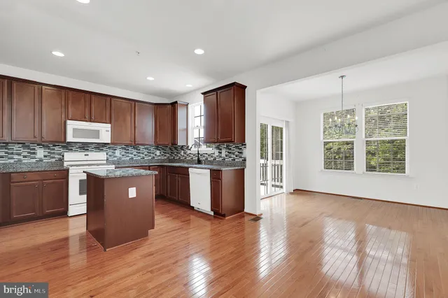 a large kitchen with stainless steel appliances granite countertop a stove a sink dishwasher a microwave oven and a wooden cabinets