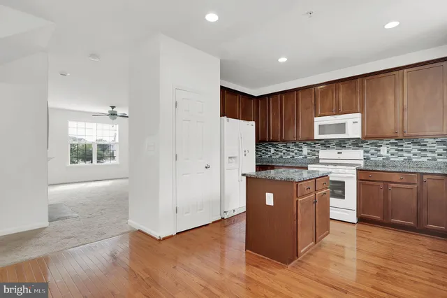 a kitchen with granite countertop wooden cabinets and white appliances