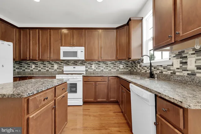 a kitchen with granite countertop wooden cabinets and white appliances