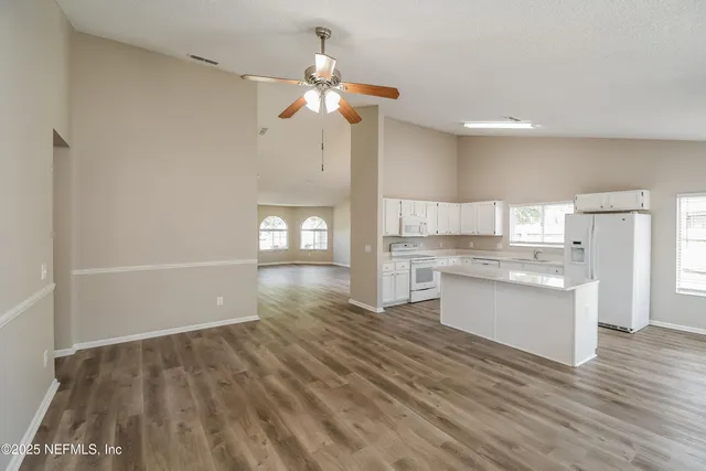 a view of kitchen with granite countertop cabinets and white appliances