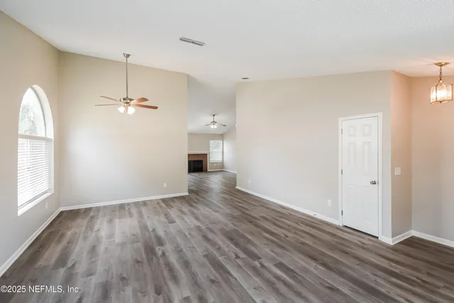 a view of an empty room with a window and wooden floor