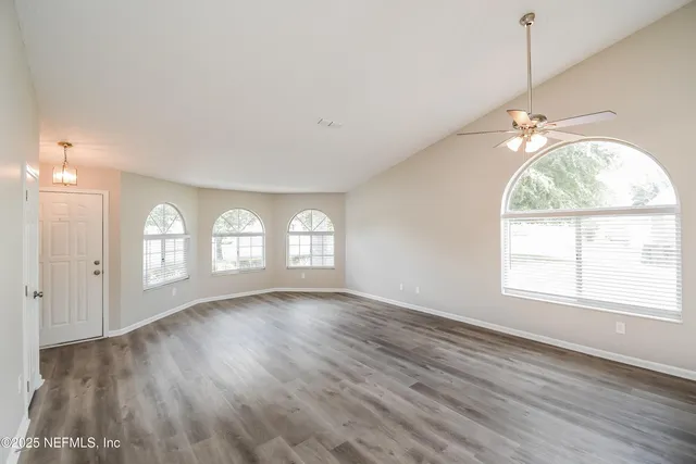 a view of empty room with wooden floor and fan