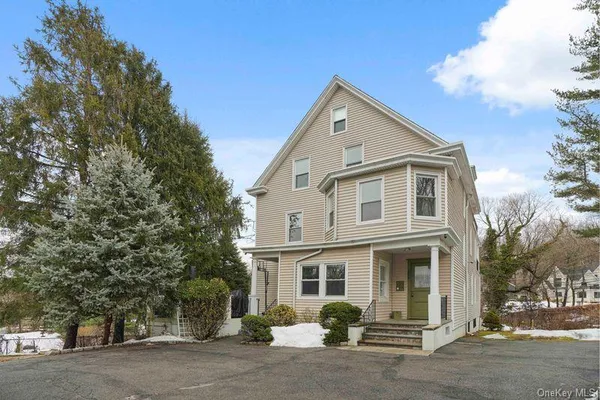 a view of a white house with large windows and a large tree