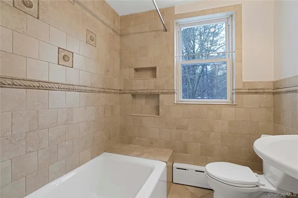 a bath room with a toilet a bath tub and a shower