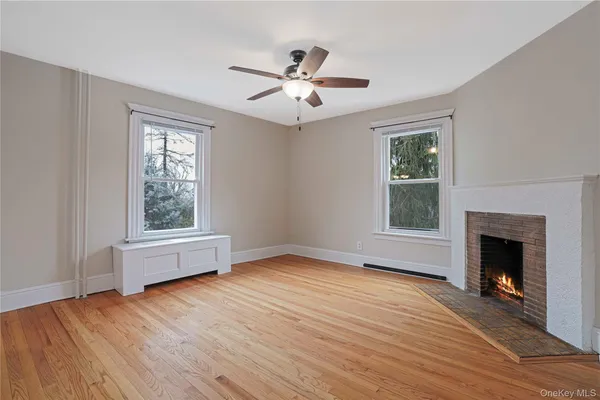 an empty room with wooden floor a chandelier fan and windows