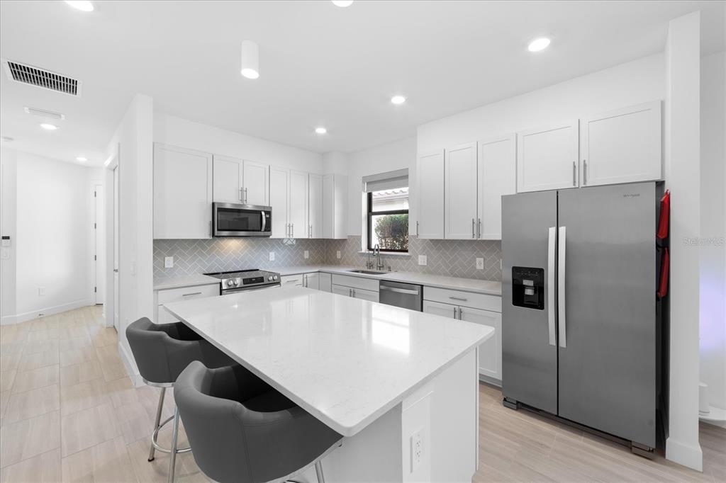 6713 Alstead Circle Lakewood Ranch, FL 34202 - Photo 8 of 86 a kitchen with stainless steel appliances granite countertop a refrigerator a stove a sink a dining table and chairs