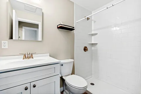 a bathroom with a sink a toilet a mirror and shower