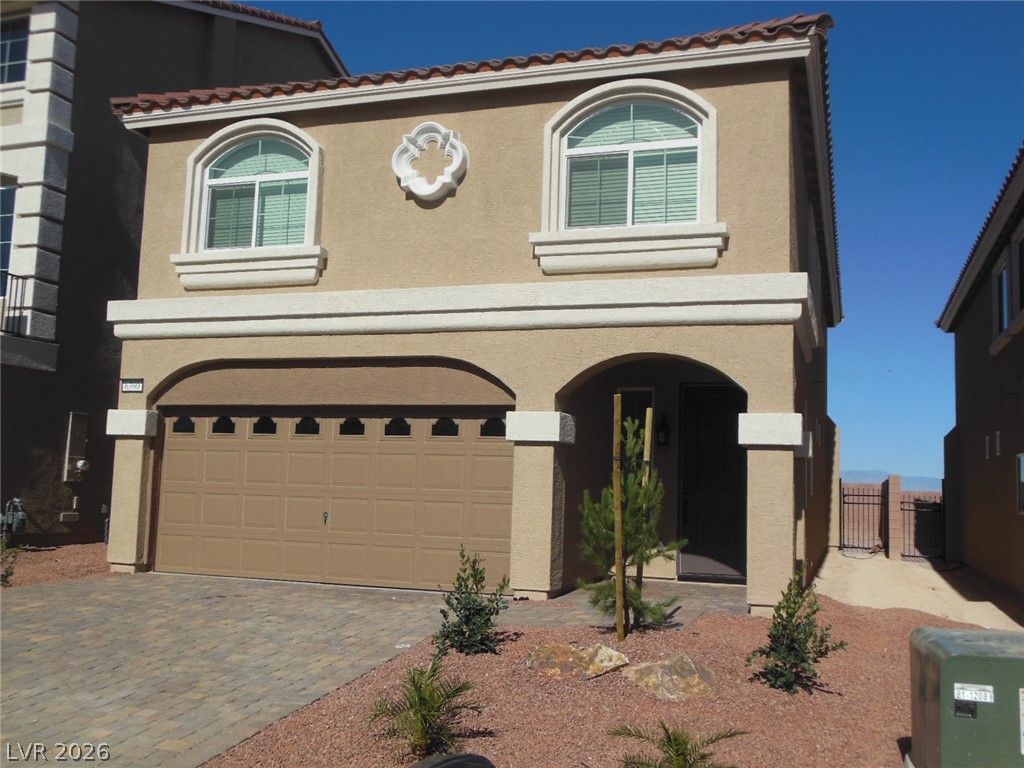 An inviting facade with arched details and a patterned driveway offers charming curb appeal.