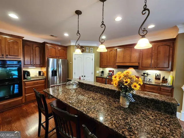 a kitchen with stainless steel appliances granite countertop a sink a stove and a wooden cabinets