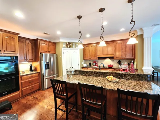 a kitchen with stainless steel appliances granite countertop a stove a refrigerator a kitchen island a sink and a refrigerator