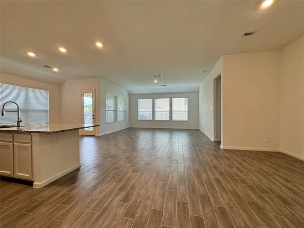 a view of an empty room with window and wooden floor