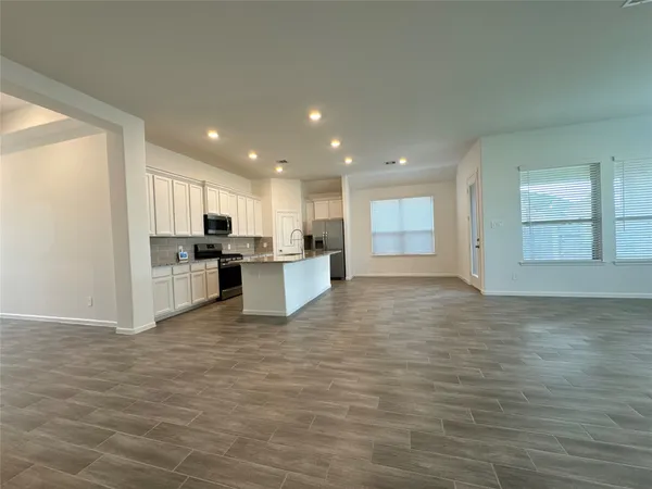 a view of kitchen with kitchen island wooden floor center island and stainless steel appliances