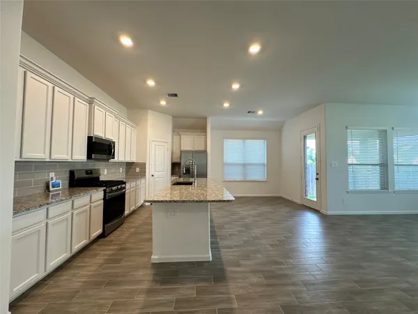 a large kitchen with stainless steel appliances granite countertop a large counter top and a stove top oven