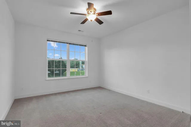 an empty room with a window and a fan