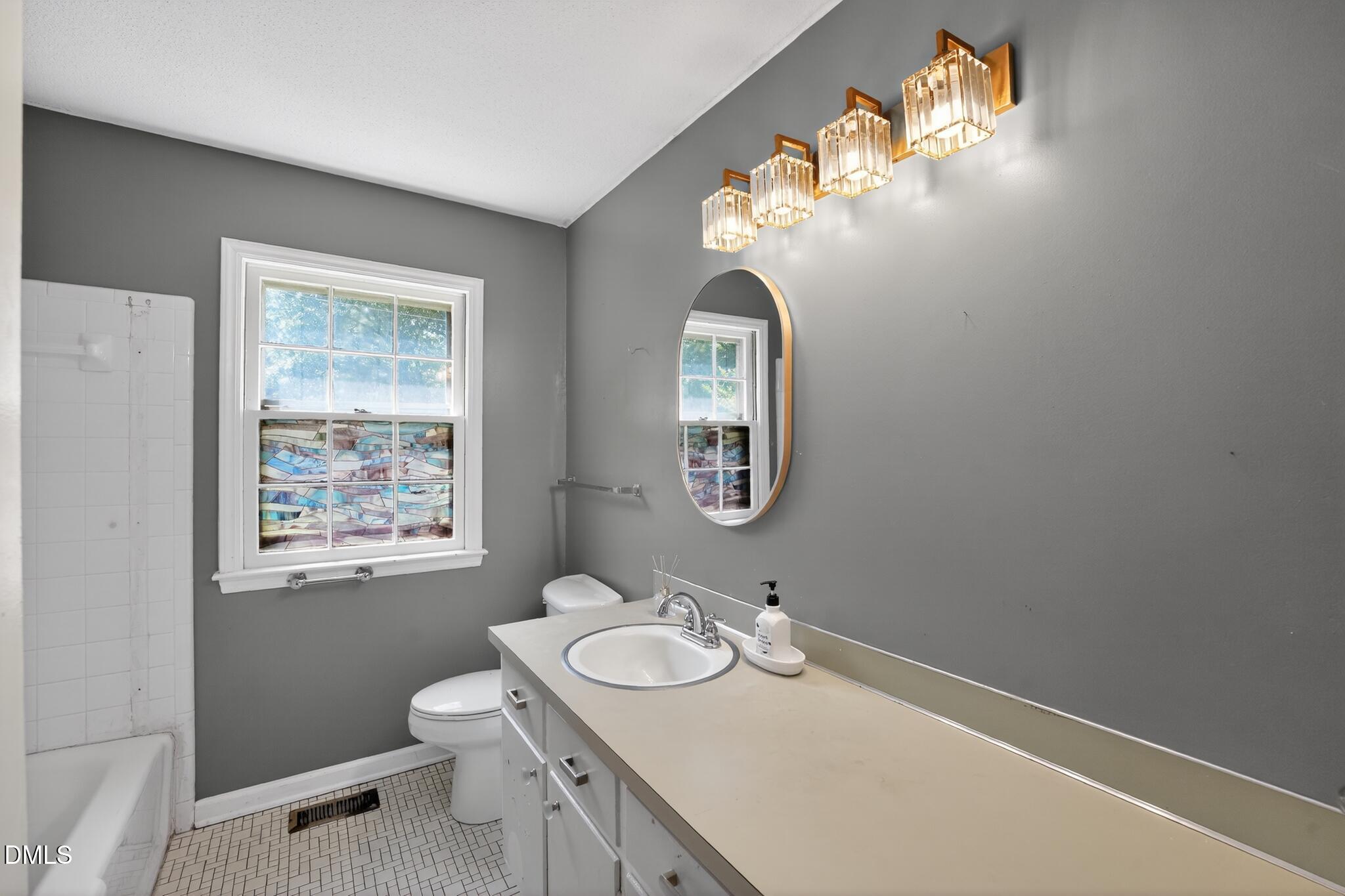 1034 Jerome Road Durham, NC 27713 - Photo 28 of 35 a bathroom with a granite countertop toilet a sink and a mirror