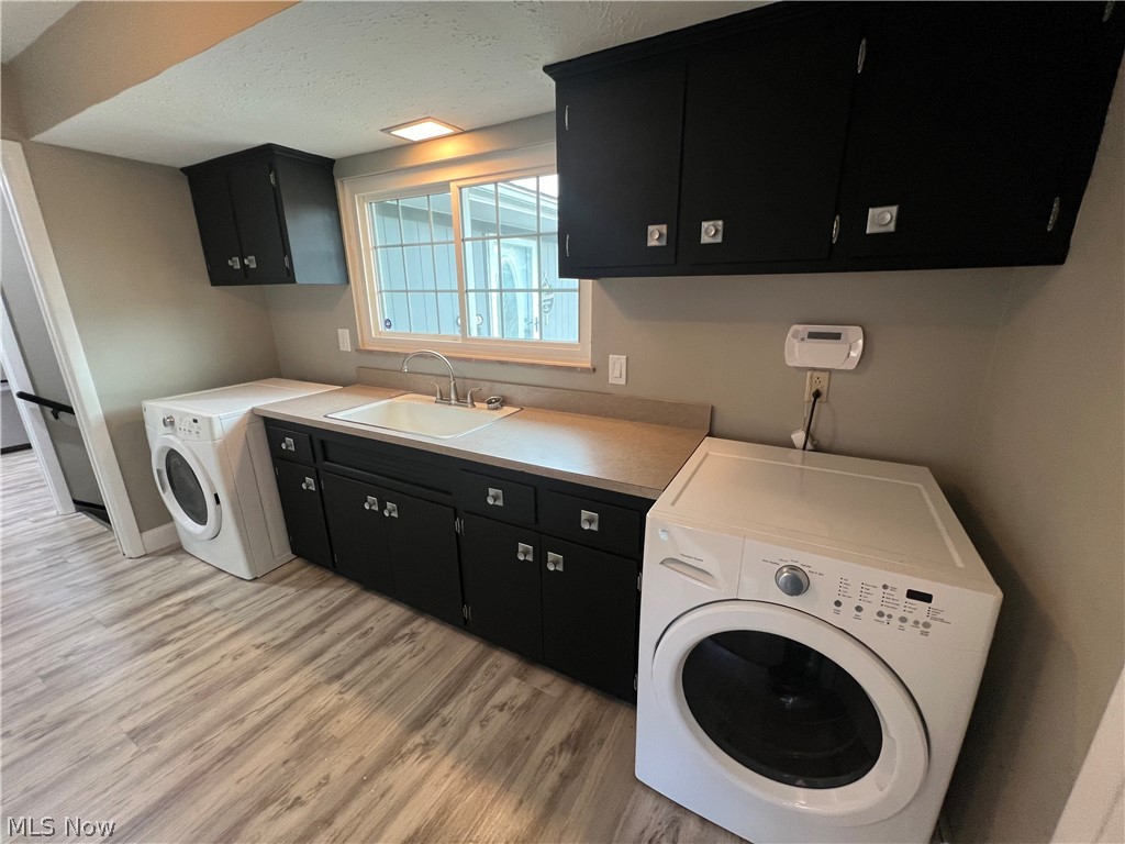 7475 Selwick Drive Parma, OH 44129 - Photo 22 of 29 Clothes washing area with sink, light wood-type flooring, and cabinets