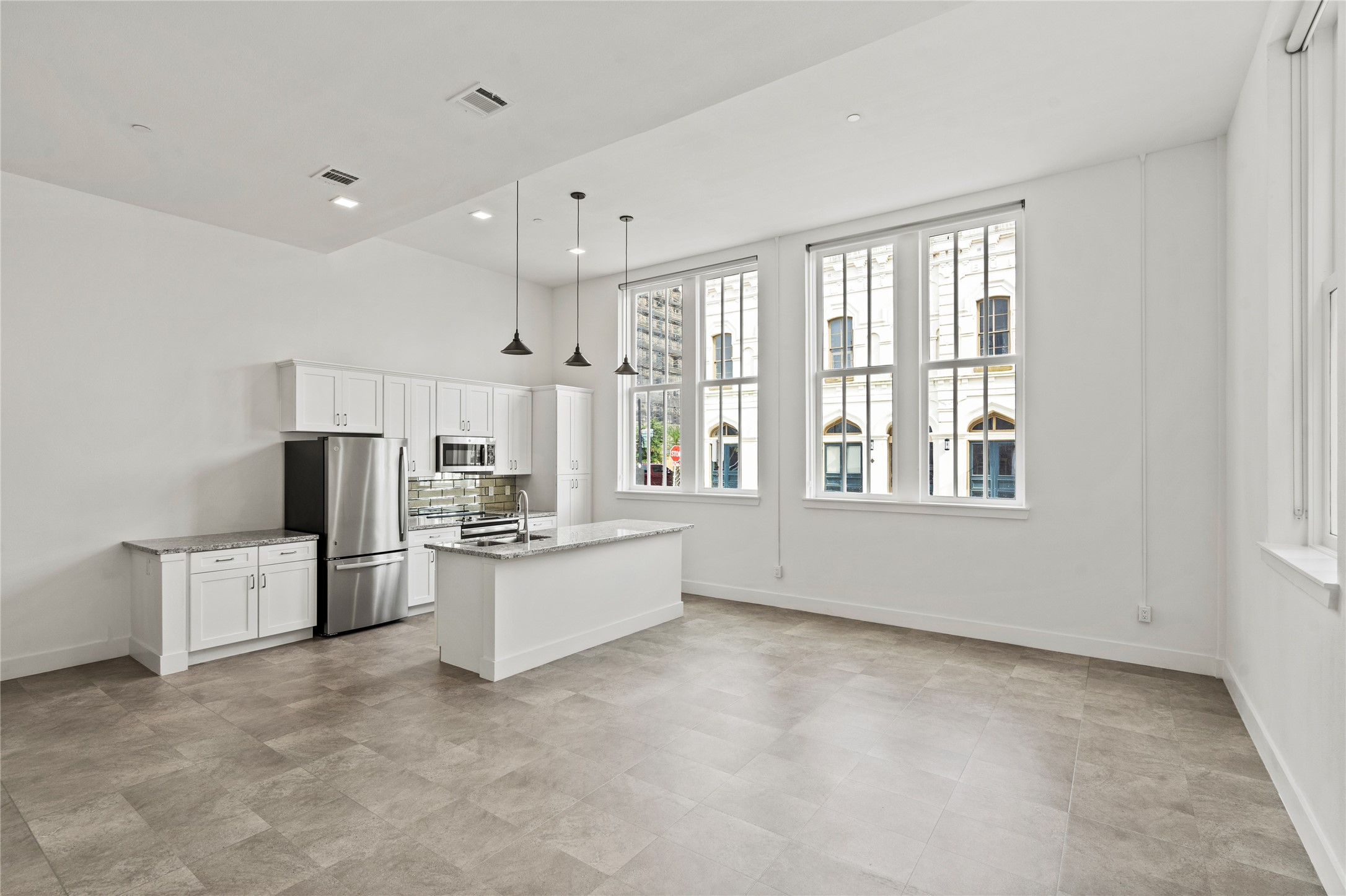 2102 Mechanic Street, Unit 101 Galveston, TX 77550 - Photo 13 of 28 a large white kitchen with stainless steel appliances granite countertop a stove and a refrigerator